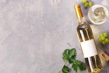 A bottle of white wine with a label, grapes and cork. Top view.