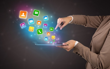 Hand holding tablet and application icons falling inwards
