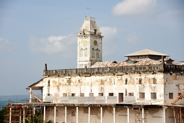 Vista de un costado a lo lejos Museo del Palacio o Palacio del Sultán en construcción sus paredes de color amarillo desteñidas por el sol, cielo azul claro y lindas nubes blancas en Zanzibar Tanzania 