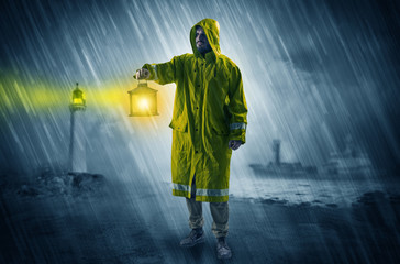 Man at the coast coming in raincoat with glowing lantern concept
