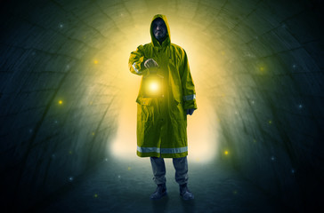 Ugly man in raincoat walking with glowing lantern in a dark tunnel