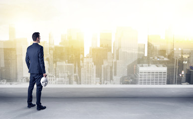 Businessman standing with his back on a roof with objects in his hand
