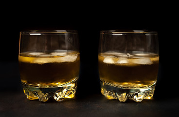 two glasses of whiskey with ice on the concrete
