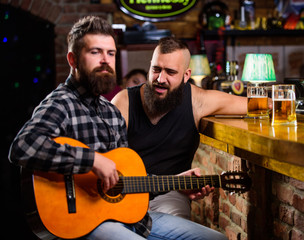 Fototapeta na wymiar Friday relaxation in bar. Friends relaxing in bar or pub. Real men leisure. Hipster brutal bearded spend leisure with friend in bar. Man play guitar in bar. Cheerful friends relax with guitar music