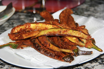 fried eggplants in breading on a white plate in the kitchen