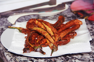 fried eggplants in breading on a white plate in the kitchen
