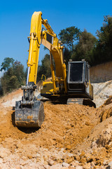 Obraz premium Industrial excavator working on construction site to clear the land of sand and soil