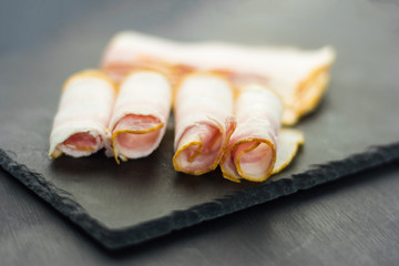 fresh tender bacon cut into thin slices on a stone Board
