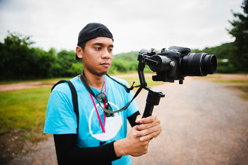 Young man holding camera shooting video at outdoor