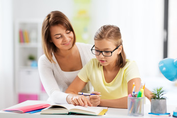 Fototapeta premium education, family and learning concept - mother and daughter doing homework together at home