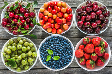 Fresh berry fruits in a bowls, flat lay. Variety of berries, background