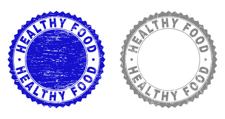 Grunge HEALTHY FOOD watermarks isolated on a white background. Rosette seals with grunge texture in blue and gray colors. Vector rubber stamp imitation of HEALTHY FOOD tag inside round rosette.