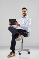 business, technology and people concept - smiling indian businessman with tablet computer sitting...