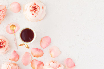 Stylish Cup of coffee with pink roses flowers and petals. Flatlay, top view on pastel concrete background