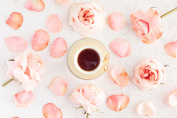 Stylish Cup of coffee with pink roses flowers and petals. Flatlay, top view on pastel concrete background