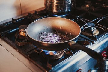 Onions cooking in frying pan on the gas stove