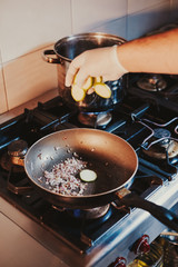 Chef dropping sliced cucumber in to a frying pan