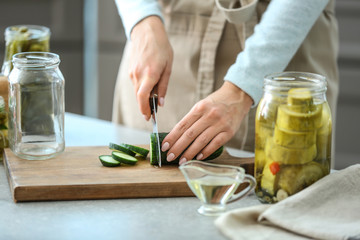 Woman preparing fresh cucumbers for fermentation in kitchen