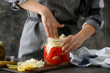 Woman preparing fresh vegetables for fermentation on table
