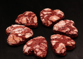 red chocolate cracked heart-shaped cookies on on a dark background. A gift for Valentine's Day, World Women's Day or Birthday