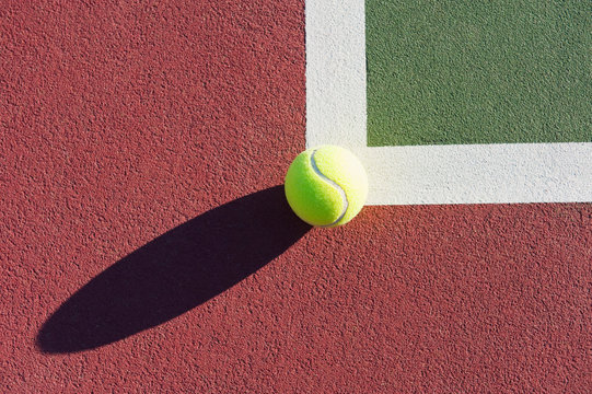 Tennis Ball Sitting on Edge of Tennis Court