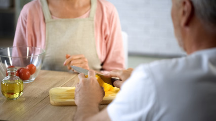 Retired couple sitting together at kitchen table, preparing lunch, relations