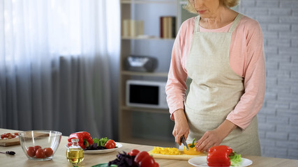 Elderly lady cutting salad, vegetarian nutrition, health care, culinary hobby