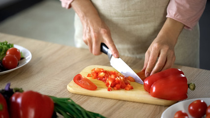 Obraz na płótnie Canvas Female chef cutting fresh pepper on board kitchen, cooking salad, culinary show