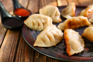 Plate with tasty Japanese gyoza on wooden table, closeup