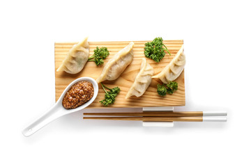 Wooden stand with tasty Japanese gyoza on white background