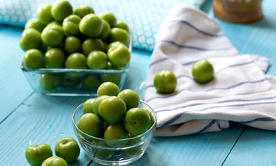 Green cherry plums on wooden table