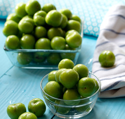 Green cherry plums on wooden table