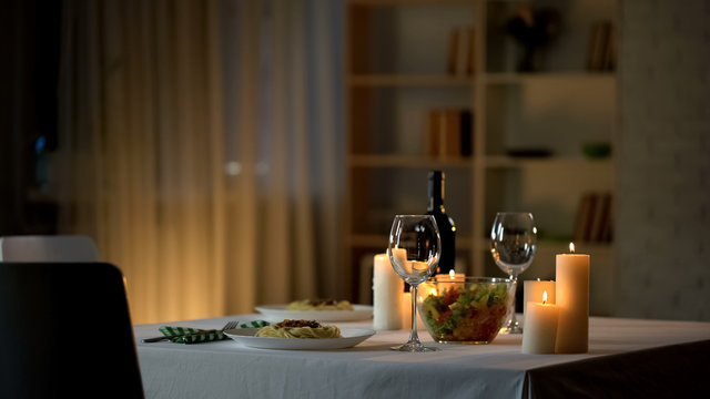 Romantic dinner table setting, wine glasses and fresh salad in bowl, home date