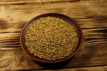 Fenugreek seeds in ceramic plate on wooden table