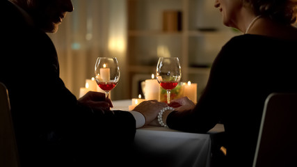 Senior couple holding hands looking each other, tender relations, closeness