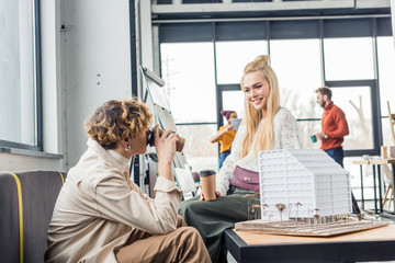 Obraz premium female and male architects with coffee to go looking at each other while working on house model in loft office