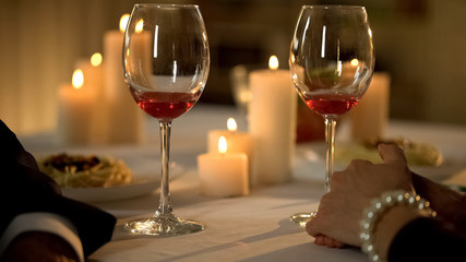 Two wine glasses on holiday table, senior romantic couple celebrating holiday