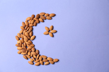 Half-moon and star made of almonds as symbol of Islam on color background