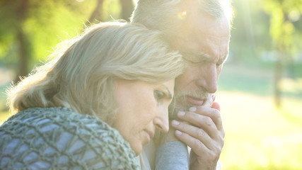 Sad senior wife embracing crying husband, relative loss, grief and sorrow