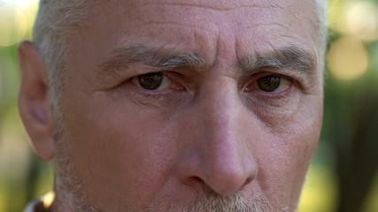 Serious pensioner looking into camera, thinking about future, retirement
