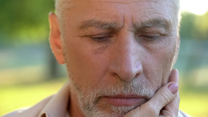 Pensive senior man thinking over life injustice, wife touching his face, support