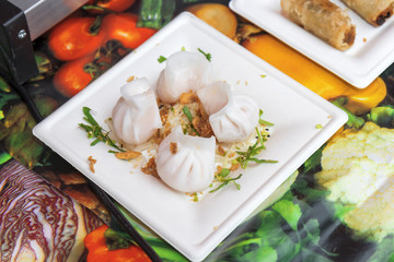 Asian street food, steamed Chinese dumplings, meat and vegetable food, fried onion, traditional asian dumplings served on plastic dish. Demonstration cooking.