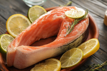 Raw salmon steak with lemon on plate, closeup