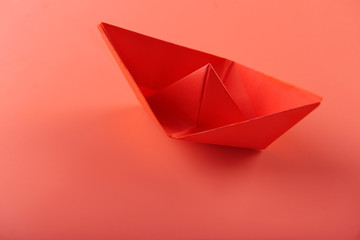 Origami boat on coral background