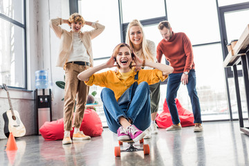 happy casual business colleagues having fun and riding skateboard in loft office