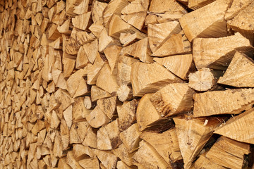 Background image of stacked, dry chopped logs used for firewood. Pile of logs ready to be used in fireplace. Alternative warming method.