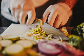 Obraz na płótnie Canvas Cook cutting leek with a knife on the board