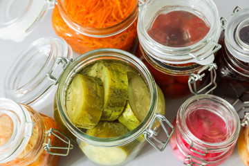 Jars with tasty fermented vegetables on light background