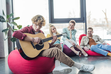 group of friends sitting on bean bag chairs and playing guitar