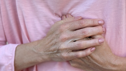 Woman holding hands on chest, sudden heart attack, health problem, emergency